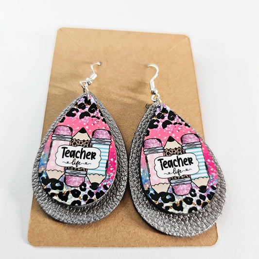 Angled view of Teacher Life earrings on a kraft card showing the gray backing layer