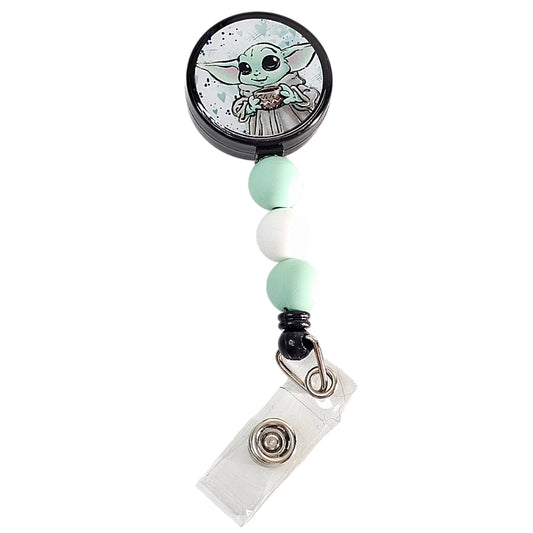 Angled view of Baby Alien fixed badge reel with green alien illustration and coordinating beads