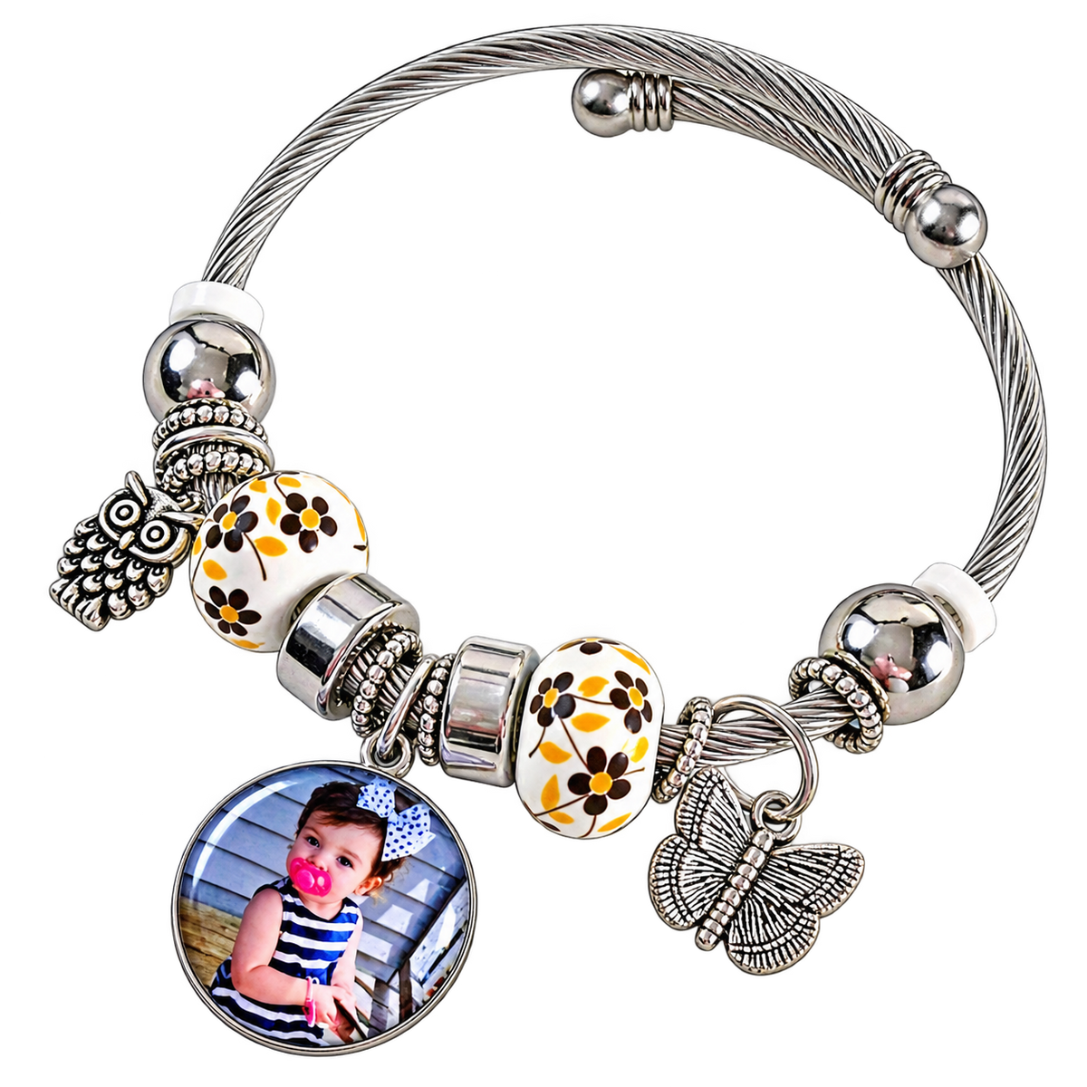 A Memory to Wear bracelet with a blank round photo setting, silver-tone cable band, yellow floral beads, and butterfly and owl charms.