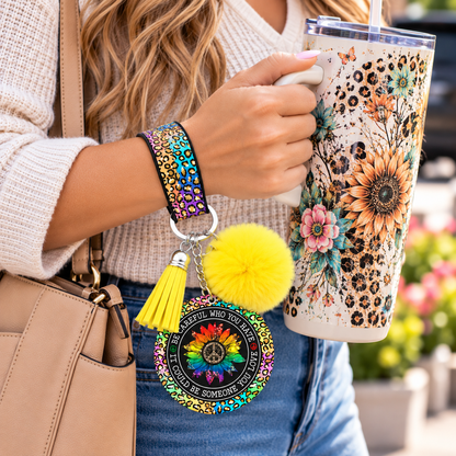 Be Careful Who You Hate wristlet worn while holding a tumbler