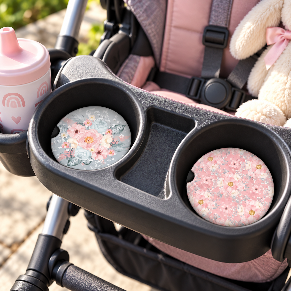 Blooms of Harmony pink and dusty blue floral car coasters displayed in the two cup holders of a child car seat