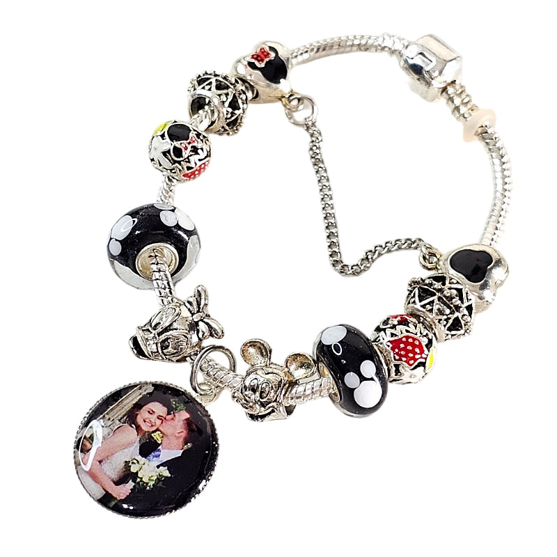 Angled Enchanted Memories personalized bracelet with a couple photo charm, black and white mouse-themed beads, and red decorative accents.