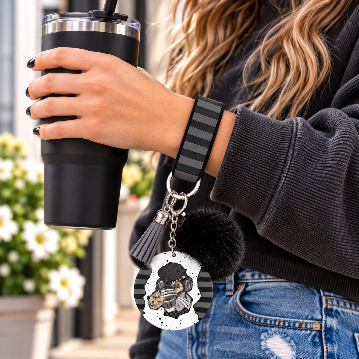Headphones On World Off wristlet worn while holding a tumbler