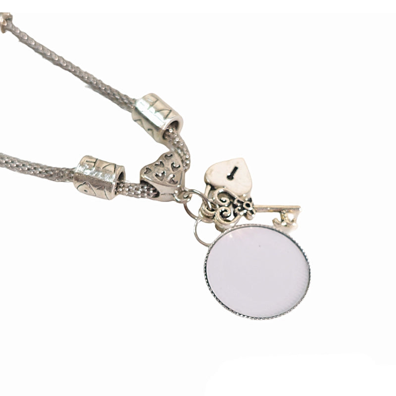 Close-up of Keys to My Heart bracelet with a blank round photo charm beside a silver-tone heart-shaped lock and decorative key.