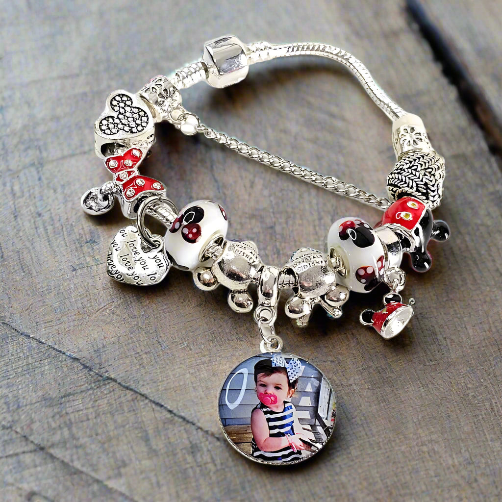 Magical Memories personalized photo bracelet resting on rustic wood, featuring a child’s portrait and red, black, and white mouse-themed beads.