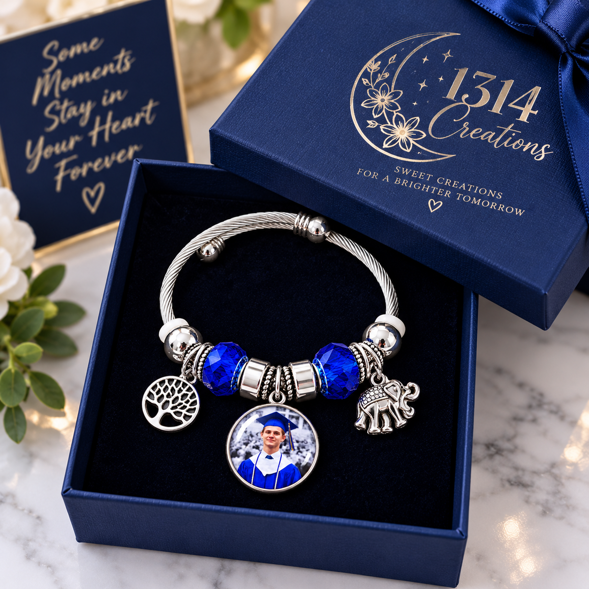 Rooted in Memories graduation photo bracelet displayed in an open navy gift box with a matching 1314 Creations branded lid.