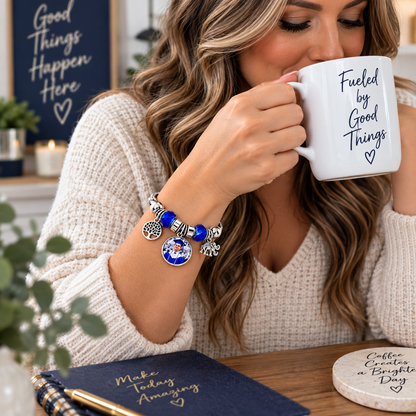 Woman drinking coffee while wearing Rooted in Memories personalized bracelet with blue beads and a round graduation photo charm.