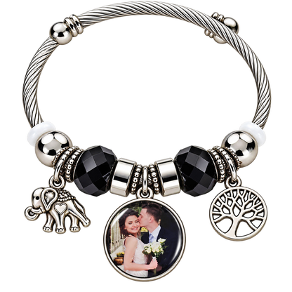 Black-and-silver personalized photo bracelet with elephant and Tree of Life charms on a black background