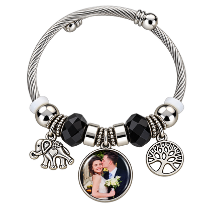 Personalized round photo charm on a black-and-silver bracelet with elephant and Tree of Life charms