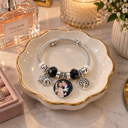 Personalized black-bead photo charm bracelet resting in a jewelry dish