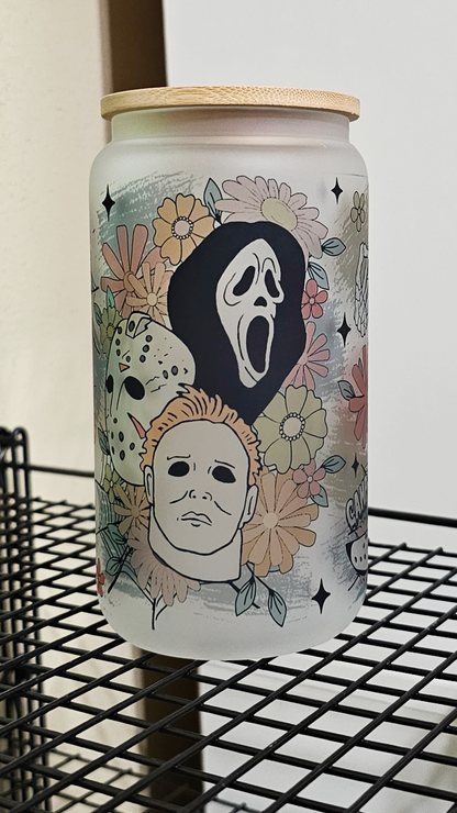 A 16oz glass tumbler featuring a blend of floral motifs and horror movie characters