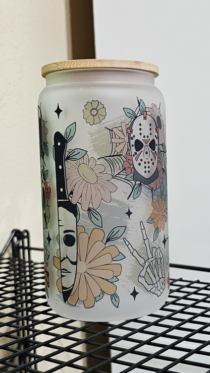 A 16oz glass tumbler featuring a blend of floral motifs and horror movie characters