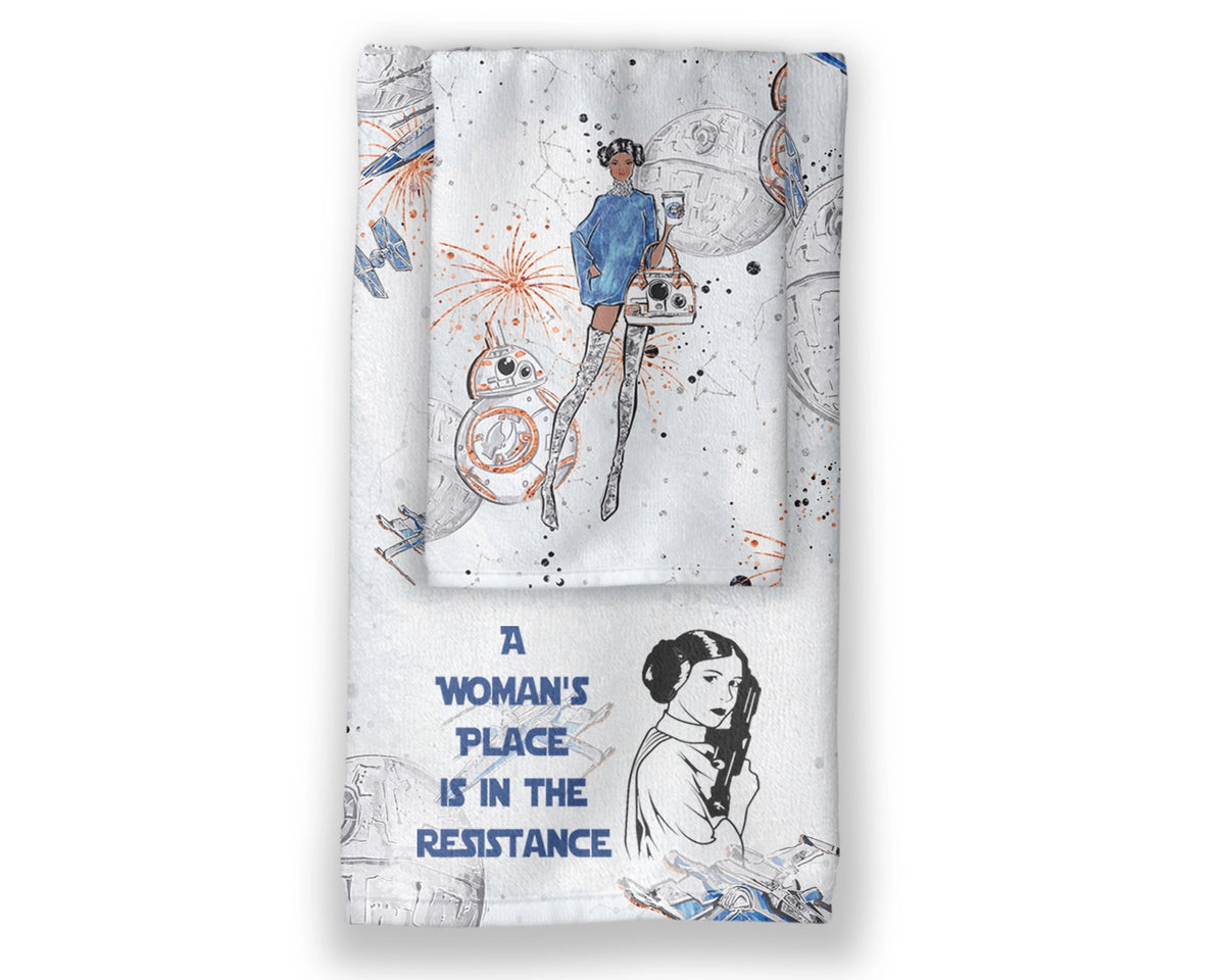A Woman’s Place Is In The Resistance two-piece hand towel set featuring space-inspired characters and blue Resistance statement lettering, layered product display