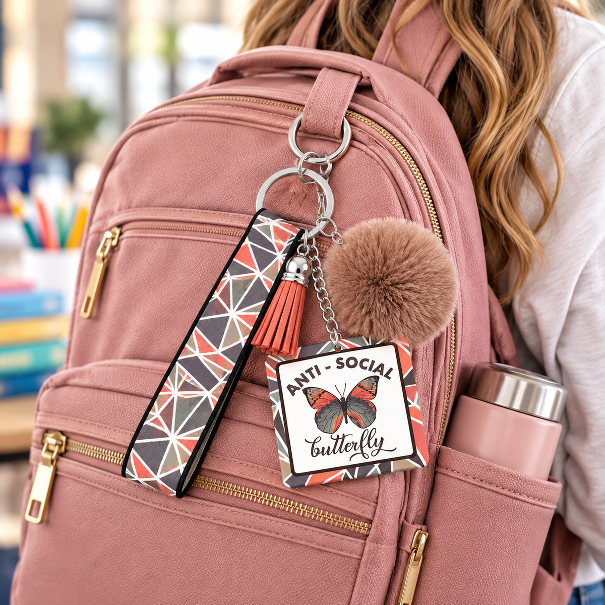 Anti-Social Butterfly keychain hanging from a pink backpack