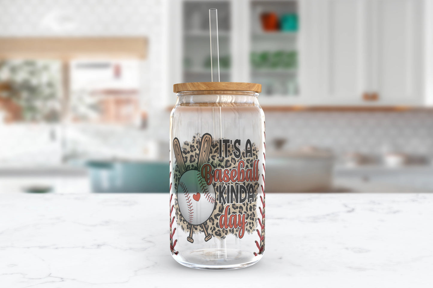 A 16oz clear glass tumbler with a baseball-themed leopard print design and the words 'It's A Baseball Kinda Day' on it