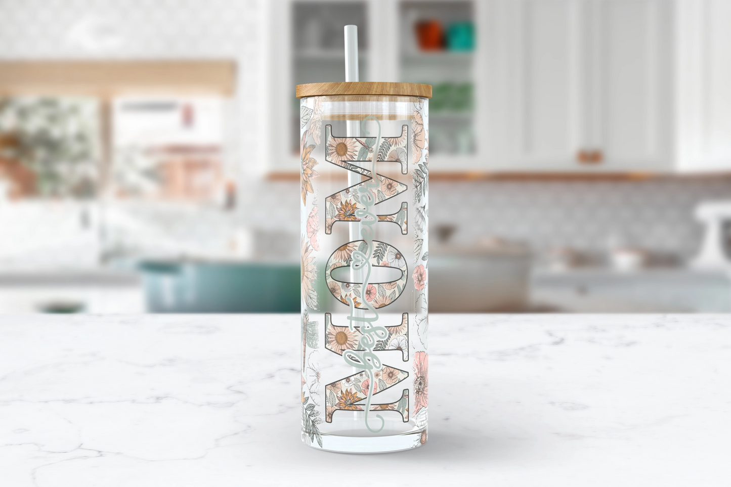 A 25oz clear glass tumbler with a boho floral and dragonfly design, featuring the word 'MOM' in bold with 'best ever' written inside the middle of the word