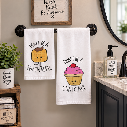 Syrup Sprinkles & Sass two-piece hand towel set featuring cowboy waffle and pink cupcake with adult-humor sayings, displayed beside bathroom sink