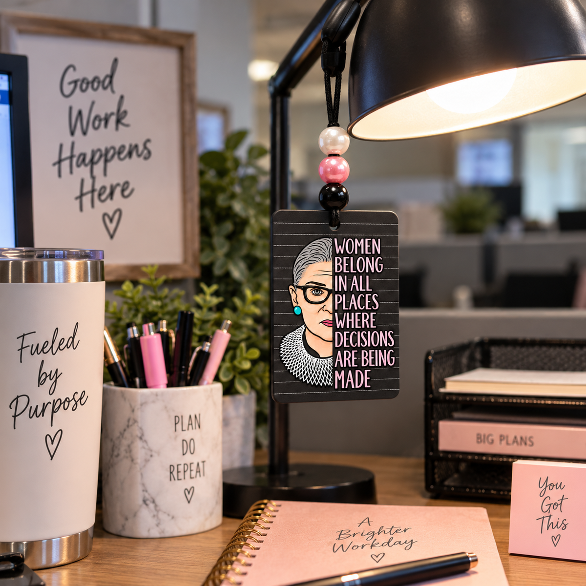 Women Belong in All Places beaded hanging air freshener, portrait side hanging from a desk lamp.