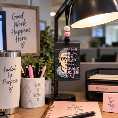 Women Belong in All Places beaded hanging air freshener, portrait side hanging from a desk lamp.